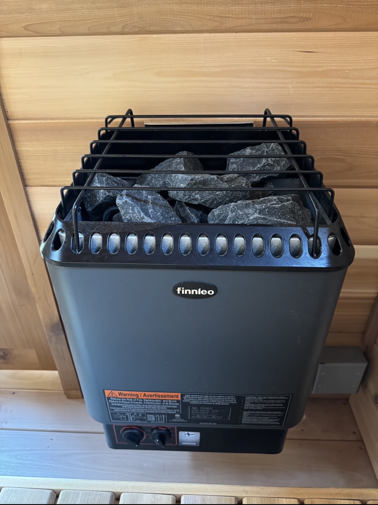 Electric sauna heater with stones against the cedar wall