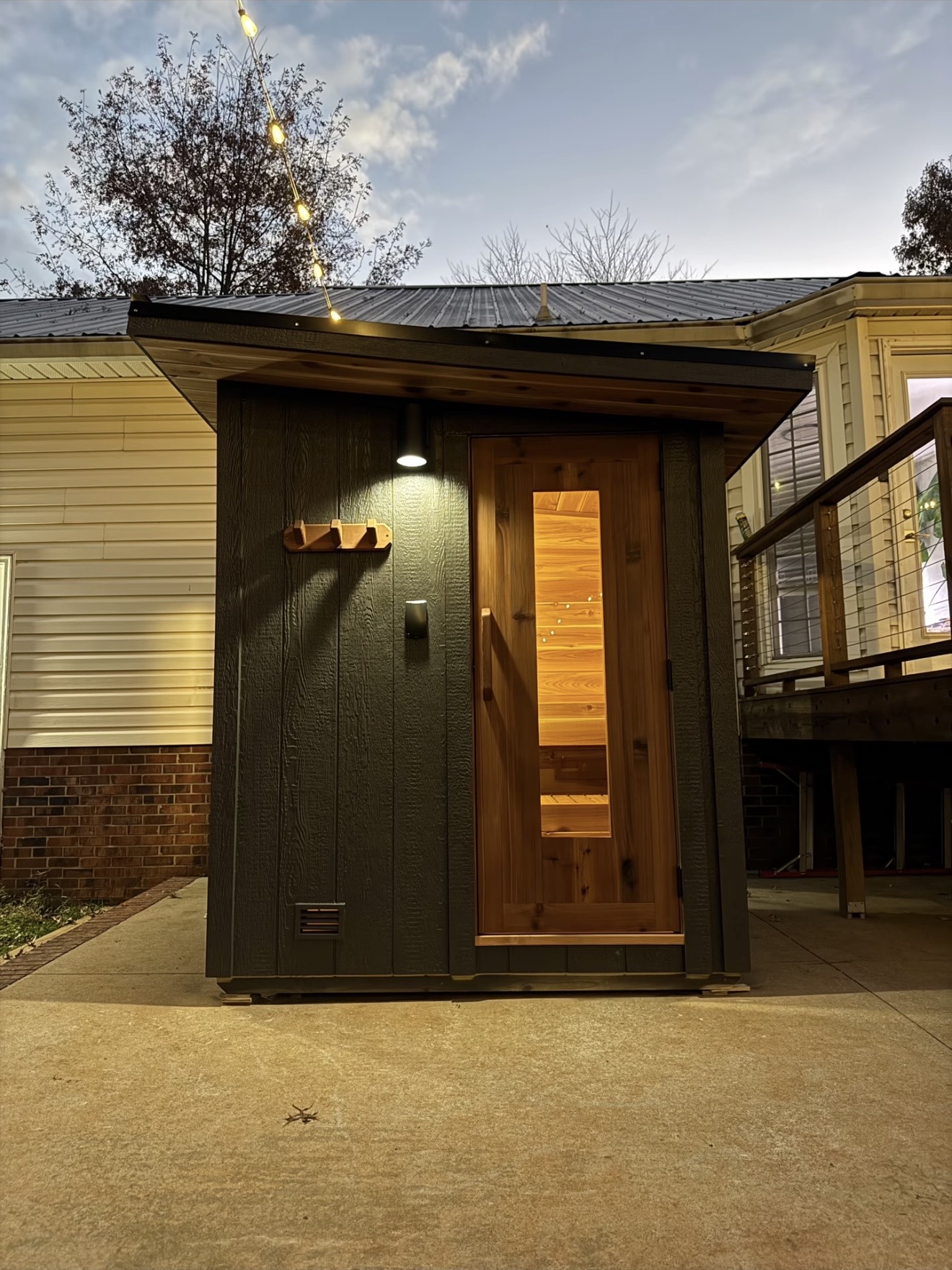 Sauna exterior at dusk with the cedar interior glowing through the door